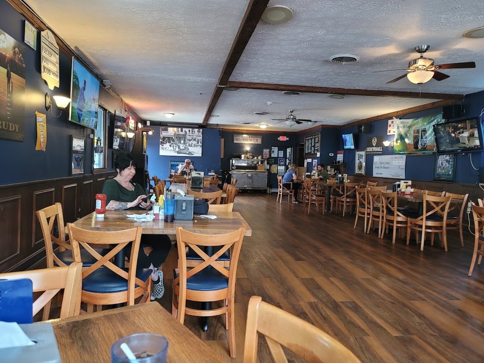 Wood-paneled sports bar with mounted screens.